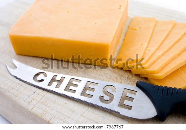 Yellow cheese sliced on top of wooden board with\
sharp knife