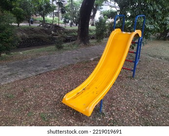 Yellow Children Toy Slide In A Residential Park. Children Game Background Concept, Education, Sport, Recreation, Outdoor, Green Space, Playground, View, Landscape, Nature, Natural, Childhood