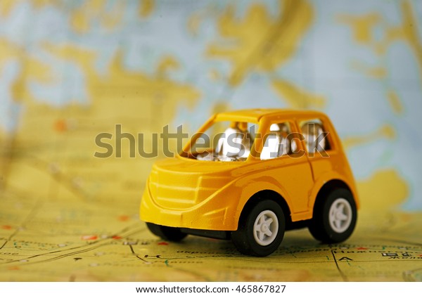 Yellow children\'s car before sending on a journey\
through the geographical\
map