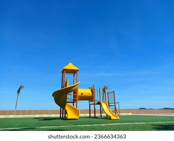 A yellow children's play area on the beach with blue skies - Powered by Shutterstock