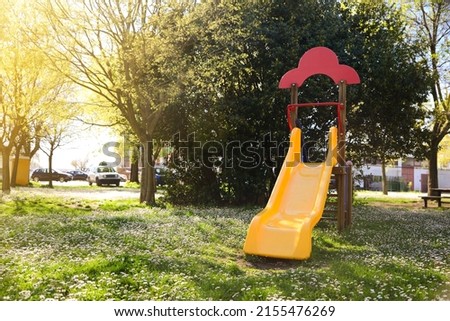Yellow children's slide and beautiful flowers in park on sunny day