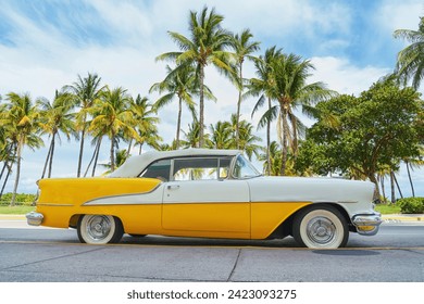 Yellow classic car on a tropical beach with palm tree, vintage process - Powered by Shutterstock