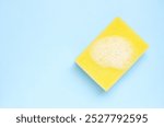 Yellow cleaning sponge with foam  on light blue background. 