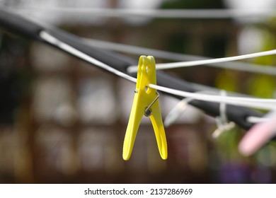 Yellow clothes peg hanging from a clothes line in the sun