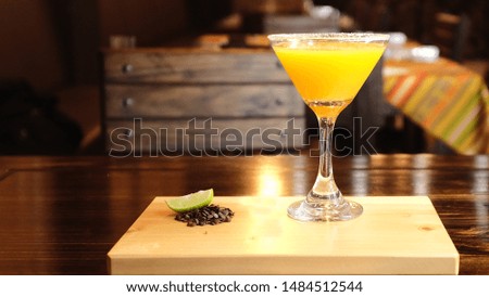 Yellow cocktail accompanied by coffee beans and lemon