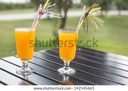 yellow cocktail with straw on wood table in summer