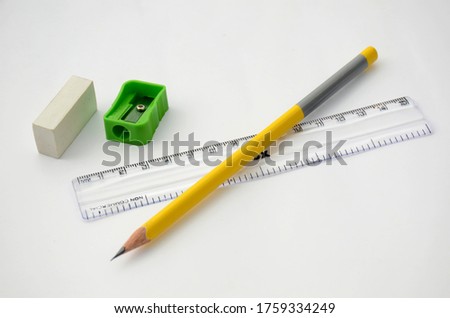 the yellow colour wooden pencil with scale and green sharpner ,eraser isolated in white background.
