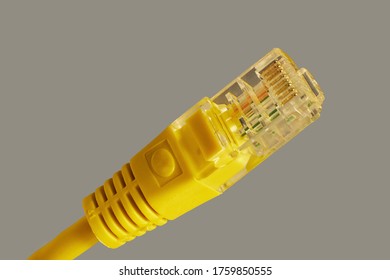 Yellow computer cable network or network cable with RJ-45 connectors on a gray background.