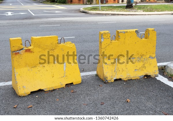 Yellow concrete Jersey barriers blocking\
vehicles from making a turn to a side road in order to avoid\
accidents from oncoming\
vehicles.