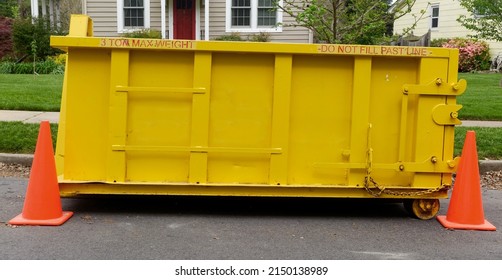 Yellow construction dumpster standing in front of neighborhood home.