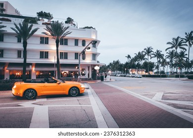 Yellow convertible muscle car pulling onto Ocean drive in miami beach at dusk - Powered by Shutterstock