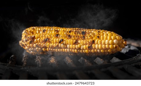 Yellow corn on the cob in sunlight on a grill with char  marks on the kernals and smoke  - Powered by Shutterstock
