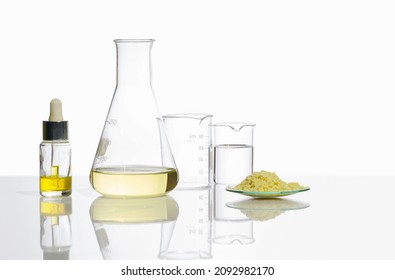 Yellow Cosmetic Liquid In Dropper Bottle, Poly Aluminium Chloride Liquid In Erlenmeyer Flask, Crystal Clear Liquid In Beaker And Sodium Sulfide Flake In Chemical Watch Glass On Laboratory Table.