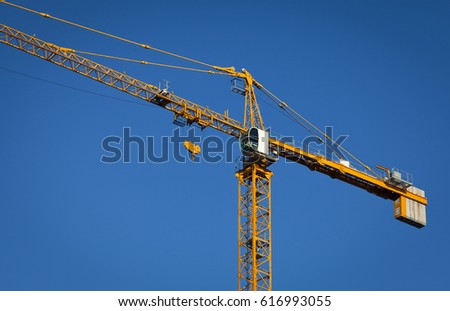 Yellow counterweight crane on blue sky background. Building construction.