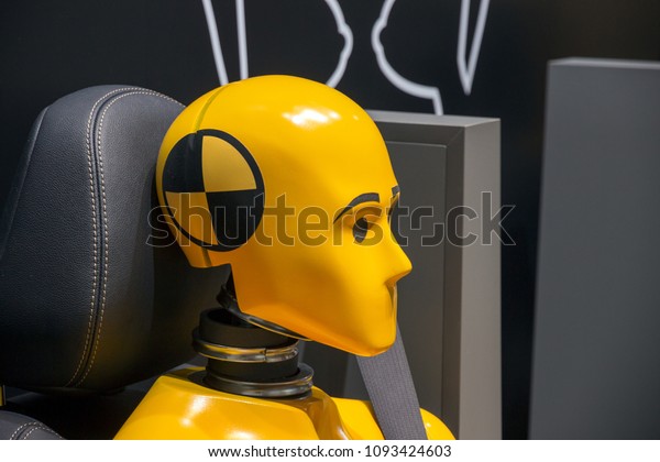 Yellow crash test dummy\
in a car seat.