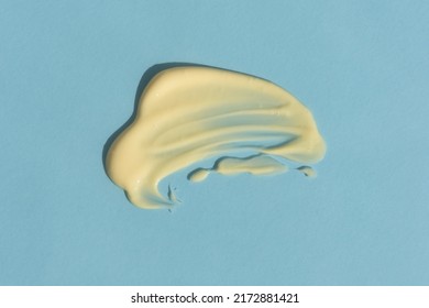 Yellow Cream Texture On A Blue Background. A Smear Of A Cosmetic Skin Care Product. Wellness And Beauty Concept. Top View