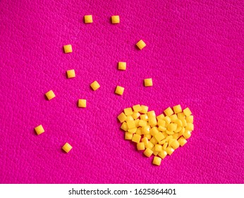 Yellow crystal craft handmade heart shape for diamond embroidery hobby rhinestone. Background with bright leather texture. Pink piece of natural tanned calfskin painted and treated. Macro. Copyspace