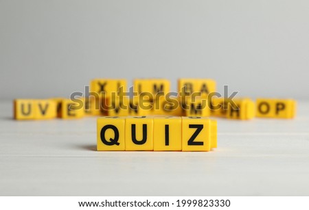 Yellow cubes with word Quiz on white table. Space for text