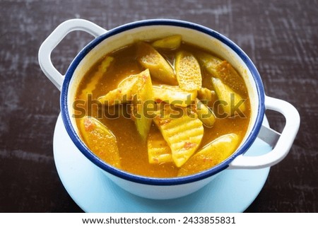 Yellow curry with fish, bamboo shoot and green taro (aaw dip) thai southern style food on wooden table. 