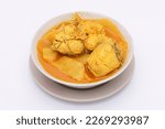 Yellow Curry with fish with coconut shoots in a bowl on a white isolated background. Thai-southern food. Top view.