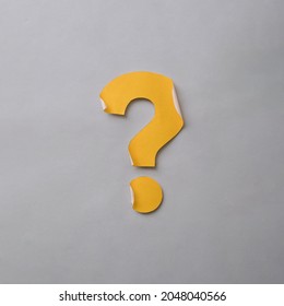 Yellow cut out question mark with curled edges over a grey card background in a conceptual image with copy space