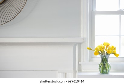 Yellow Daffodil Flowers In Glass Vase On White Fireplace Mantle