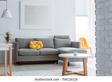 Yellow Decorative Pillow On Grey Sofa In Living Room With Brick White Wall And Simple Coffee Table
