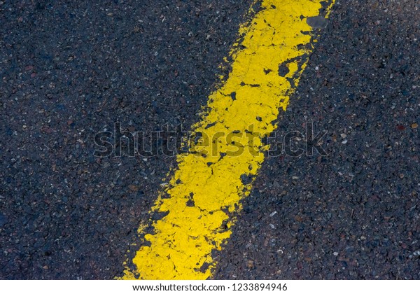 Yellow\
diagonal strip of paint on black new\
asphalt.