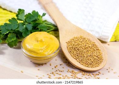 Yellow Dijon Mustard Sauce In Glass Dip With Wooden Spoon Full Of Dry Mustard Seeds On The Table In The Kitchen