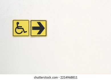 Yellow Disabled Sign And Arrow Right Pointing Sign On White Background. Handicapped Accessible Sign Of Wheelchair. Concept Of Comfortable Pathway For People Barrier-free Urban Environment In City.