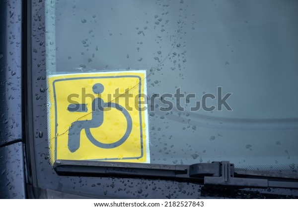 Yellow disabled sign under the car window.\
Disabled person driving. A sign designating a person with\
disabilities in motor\
transport.