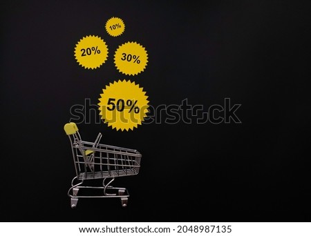 yellow discount stickers fall into the shopping cart. layout on a black background with space for text.