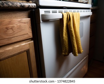 A Yellow Dish Rag Hangs On A Dirty White Oven.