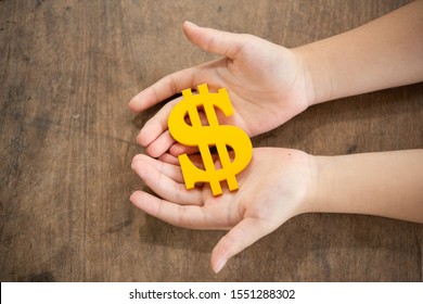 The Yellow Dollar Symbol On Hands Child For The Investment Or Saving Of People With Differences Diversity For Insurance, Education, Safety Life For Good And Stable In Future Of Family