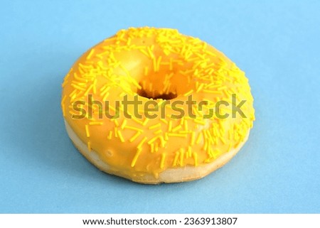 yellow donut with sugar sprinkles isolated on blue background macro  