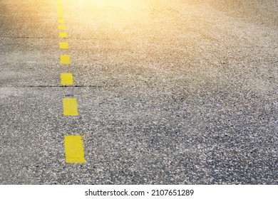 Yellow Dotted Line On An Asphalt Road And A Sun Glare.