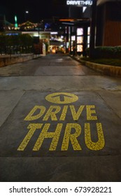 Yellow Drive Thru Sign With An Arrow Pointer. A Car Drive Into Fast Food Restaurant In The Late Of Night Then Order Some Food. Fast Food Store That Open 24 Hours Selling Burger, Fried And Nugget.