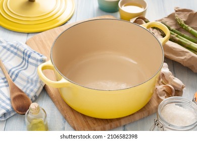 Yellow dutch oven on a wooden board with condiments around it