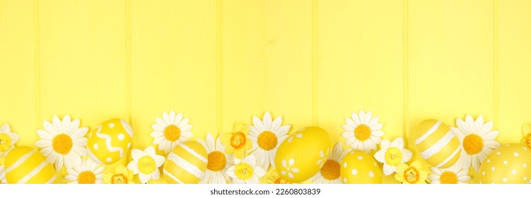 Yellow Easter eggs and white daisy flowers. Top down view bottom border against a vibrant yellow wood banner background. Copy space. - Powered by Shutterstock