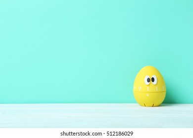 Yellow Egg Timer With Googly Eyes On A Green Background