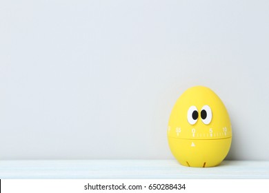 Yellow Egg Timer With Googly Eyes On A Grey Background