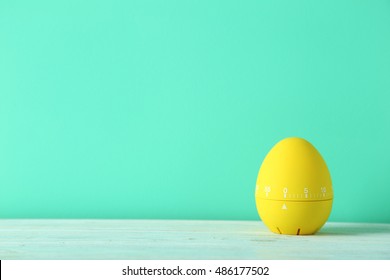 Yellow egg timer on green wooden background