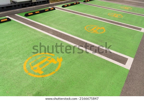 Yellow electric car symbol on green asphalt.\
Electric vehicle charging\
parking
