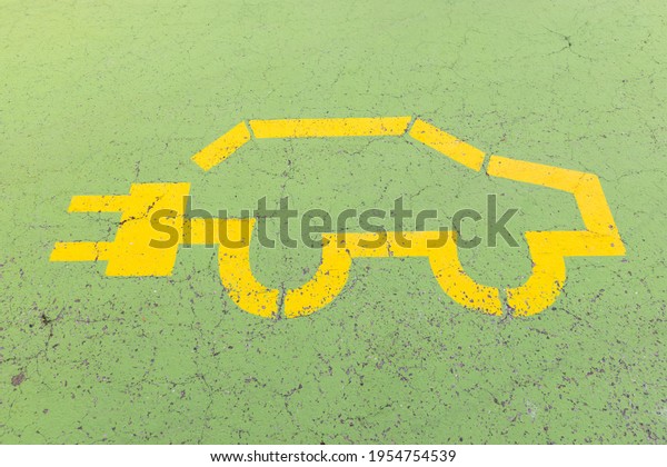 yellow electric car symbol painted on a green\
concrete floor, without\
people