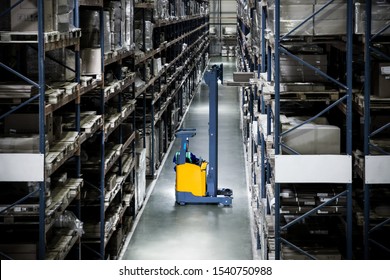 Yellow Electric Forklift Reach Truck In A Warehouse Pulls Out A Pallet From A High Shelf Against The Background Of A Bleached Warehouse