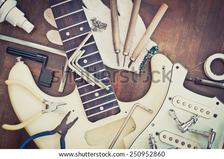 yellow electric guitar on wood in repair & luthier workshop, fixing & musical instrument repairing concept