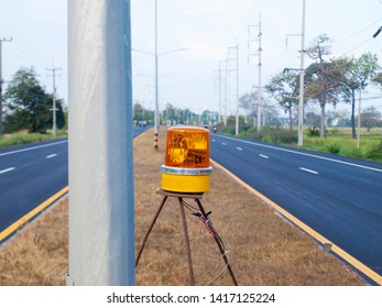 Yellow Emergency Lights Beside Metal Poles On The Middle Of The Road To Send The Yellow Light Signal Warning To Be Aware Of The Danger Of Using The Road On The Asphalt Road Background And Blue Sky.