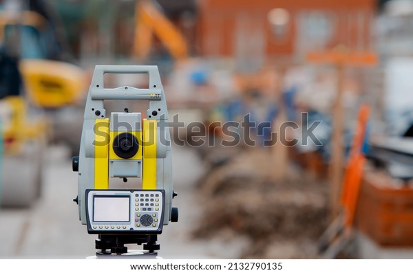 Yellow equipment set out on tripod on building site
against cloudless blue sky. Construction site surveying engineering
equipment, EDM, tacheometer set out on tripod site ready for
setting out.