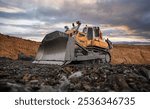 Yellow excavator in career moves overburden. Bulldozer working in an open pit. Bulldozer combs the ground, with the bright sun and nice blue sky in the background. Mining digger, mining machinery.