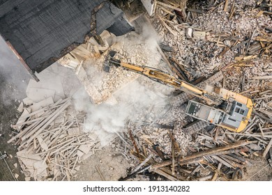 Yellow excavator destroys building. Heavy duty machine is demolishing a brick building. Demolition of the building . Demolition construction work aerial drone photo